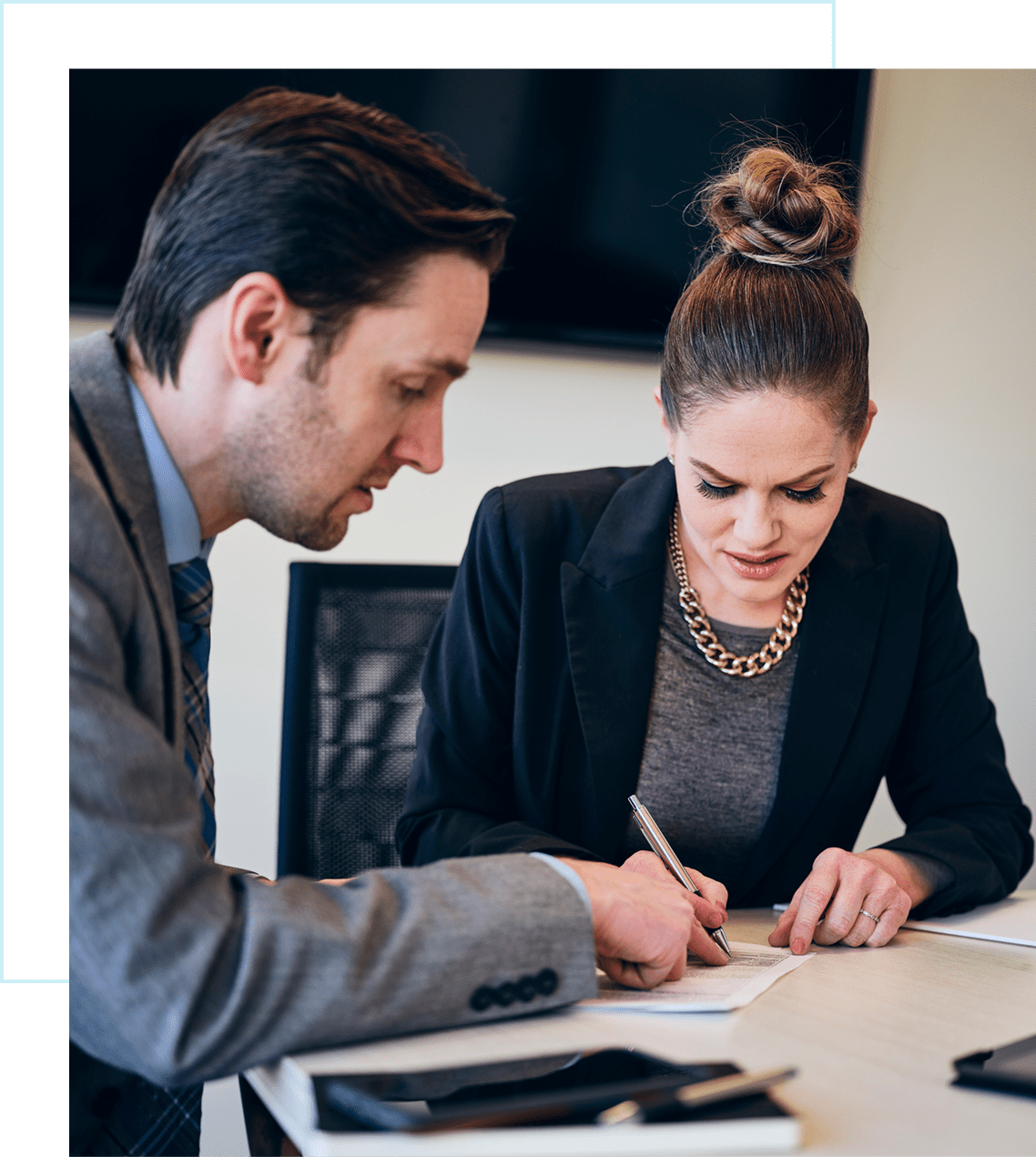 Two professionals discussing and writing documents.
